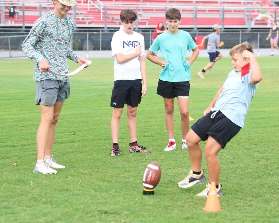 Coaches leading a group of campers on the field